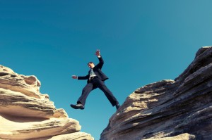 Risk concept. Businessman jumping across a ravine.